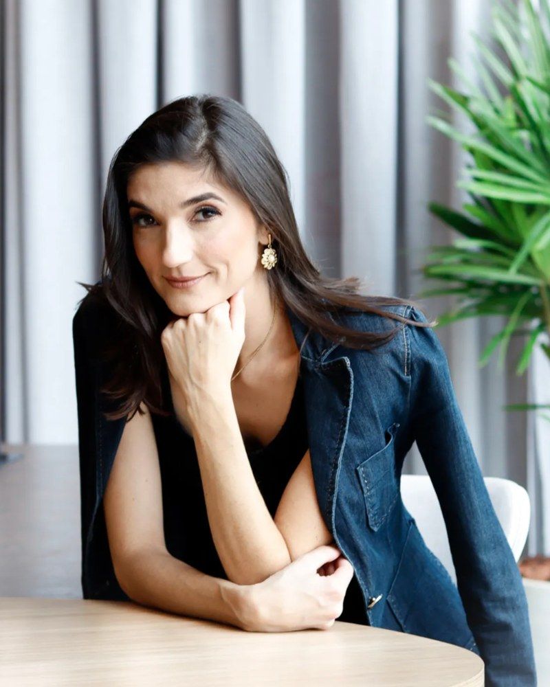 Flávia Pastorelli, arquiteta responsável pela gestão da Contemporano, apoiada numa mesa de madeira